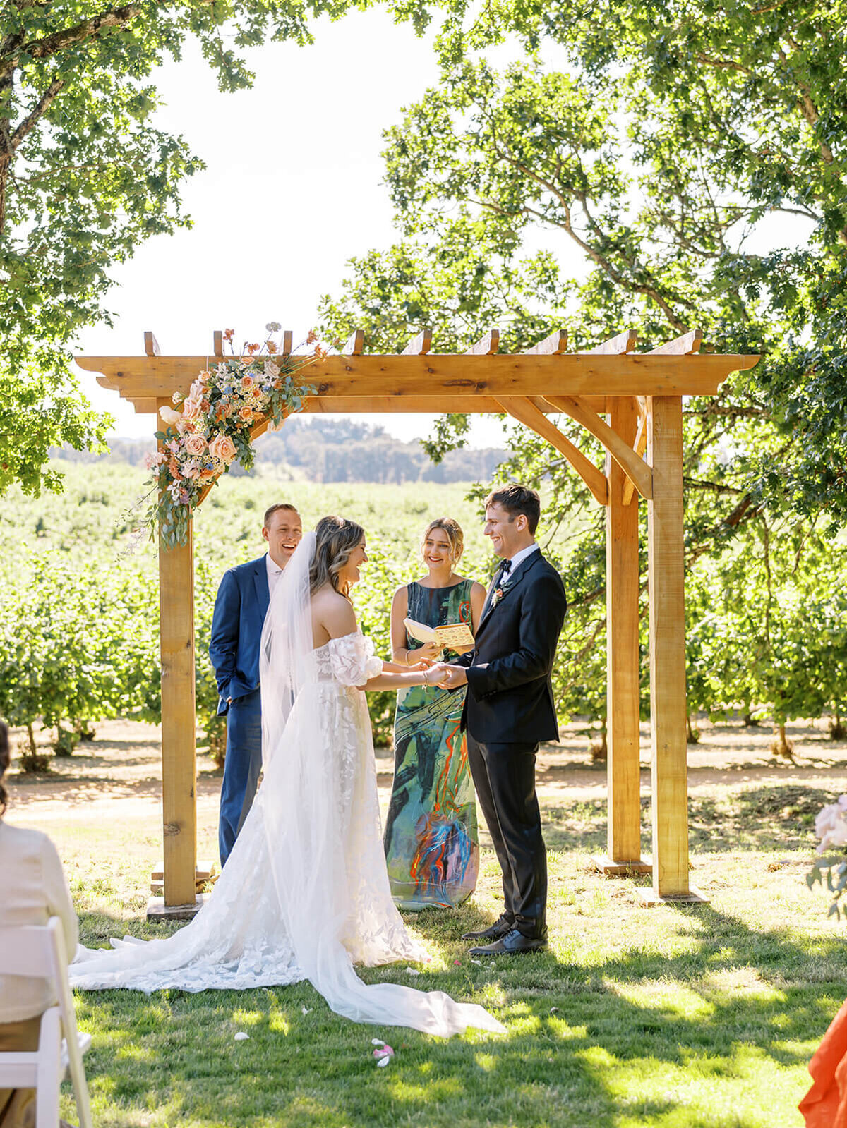 A bride and groom under an arbor during their outdoor wedding.