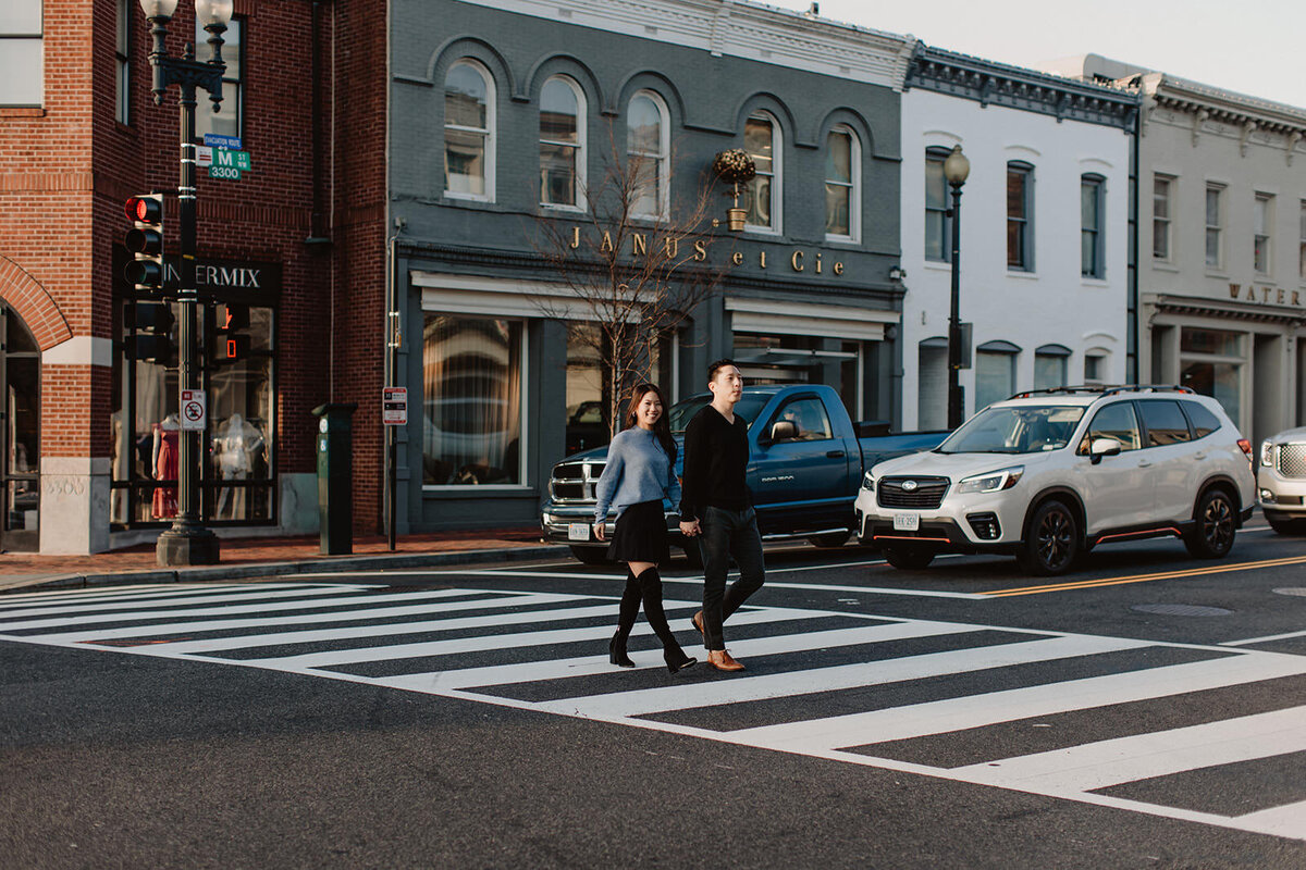 A couple holding hands and walking across a crosswalk 