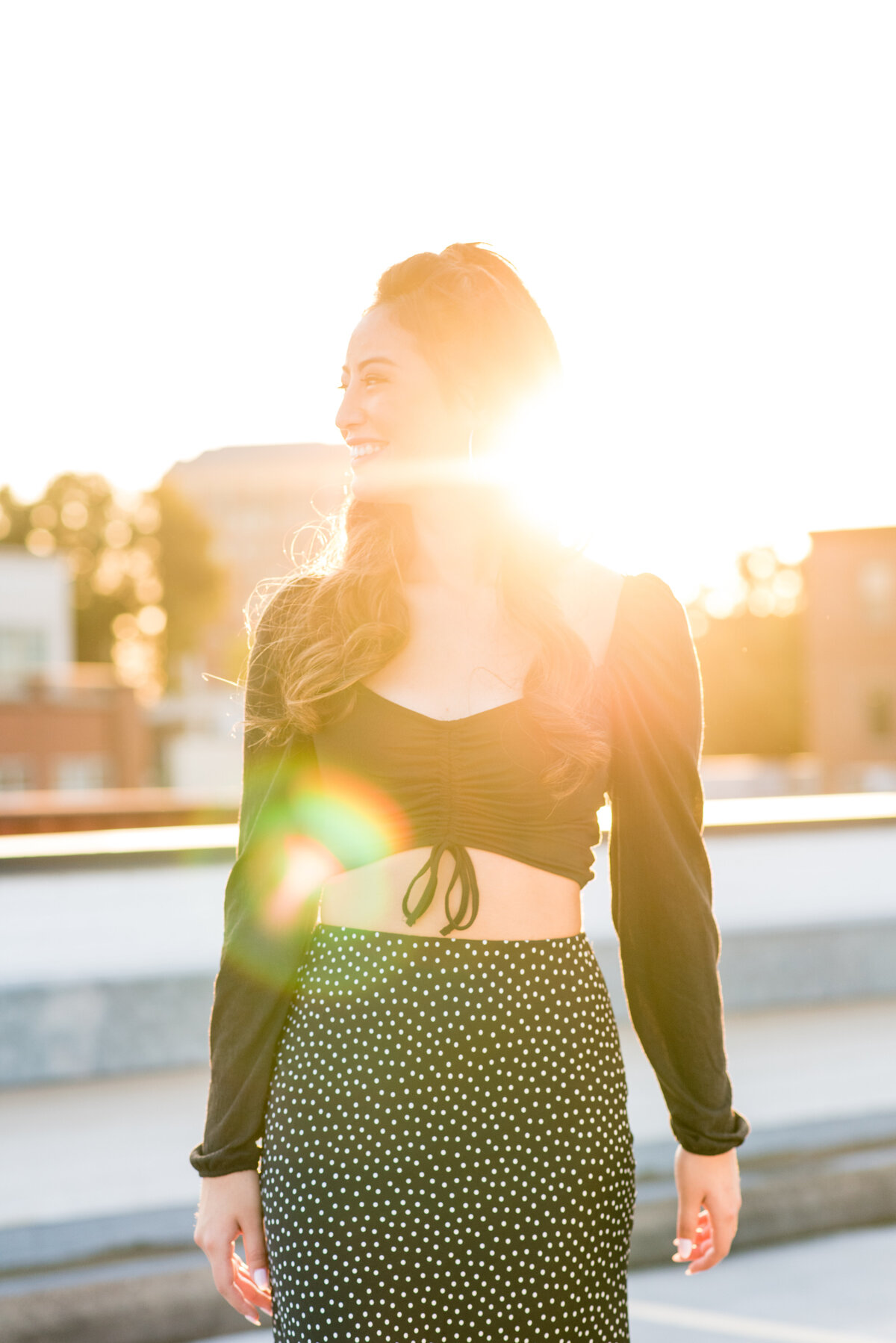 Senior girl at sunset on a rooftop with sunflare.