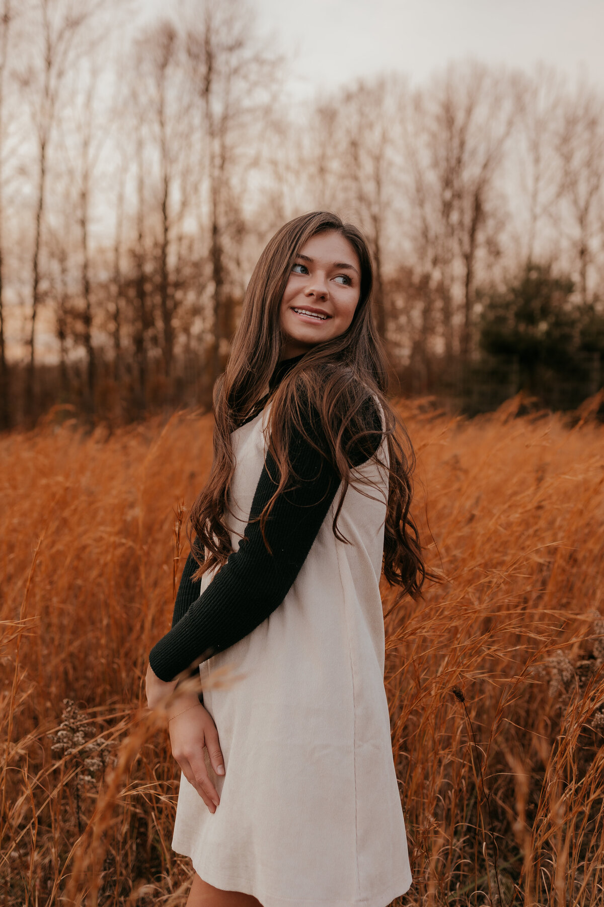 Photo of a senior in highschool posing in a field during golden hour in Bloomington , Indiana