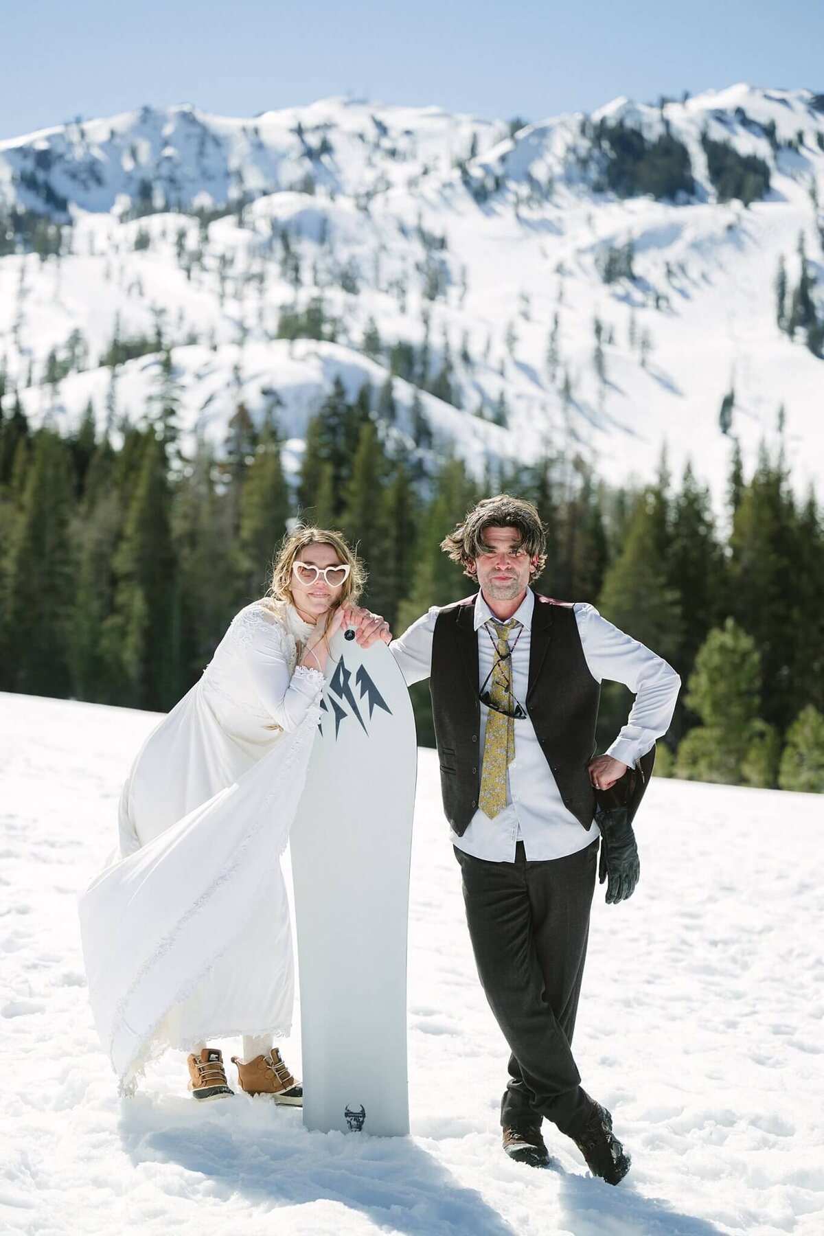 bride and groom posing with snowskate facing camera in winter elopement in Tahoe