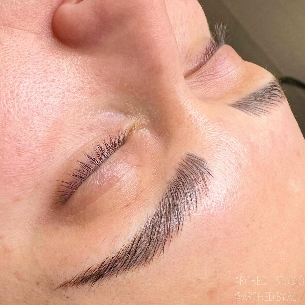 Female enhanced eyebrows that look naturally fluffy, through nicroblading services at ARCHED Coastal in Gulf Shores, Alabama.
