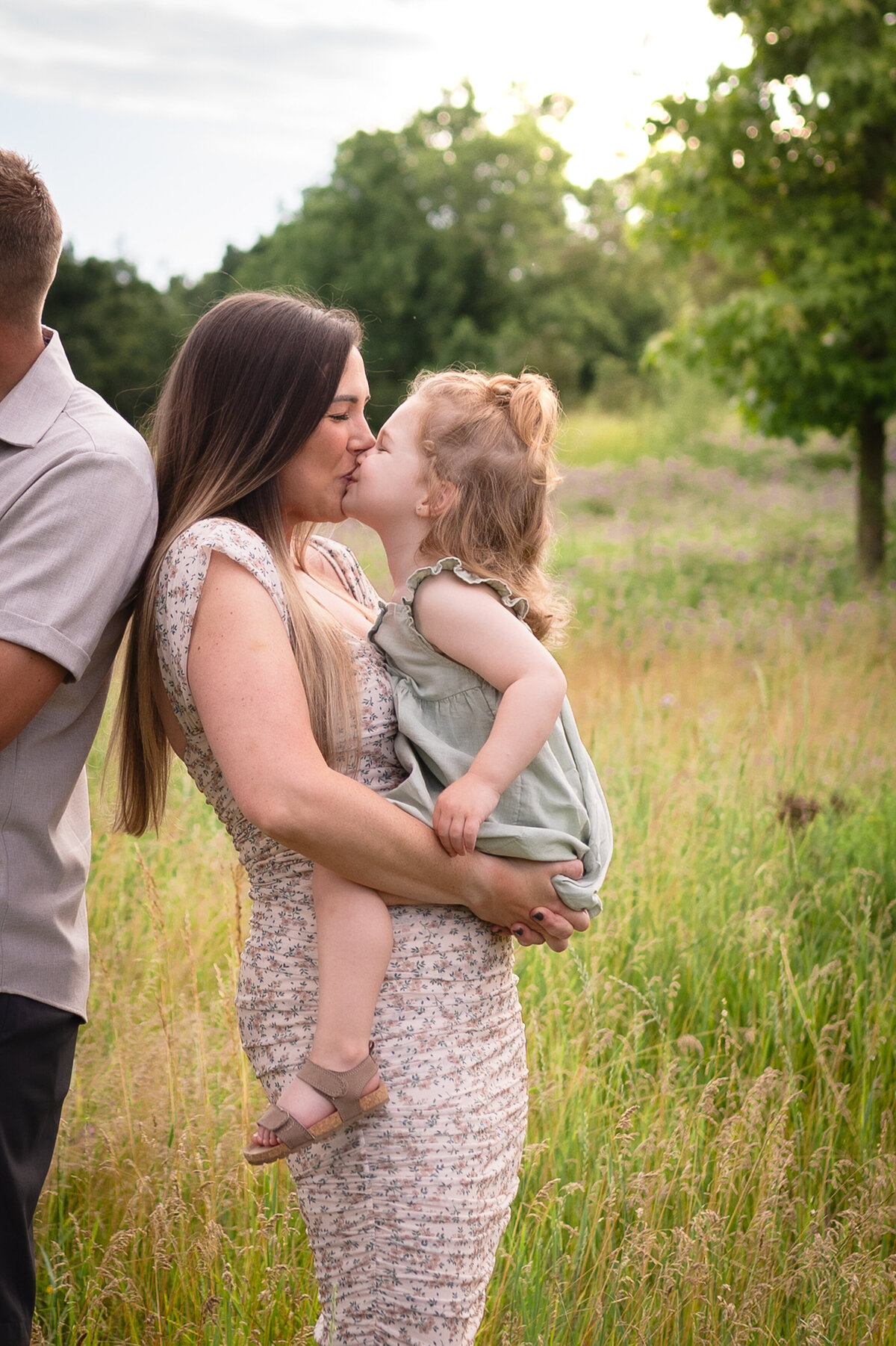 mom kissing daughter in an open grassy field at Kensington Metropark Michigan