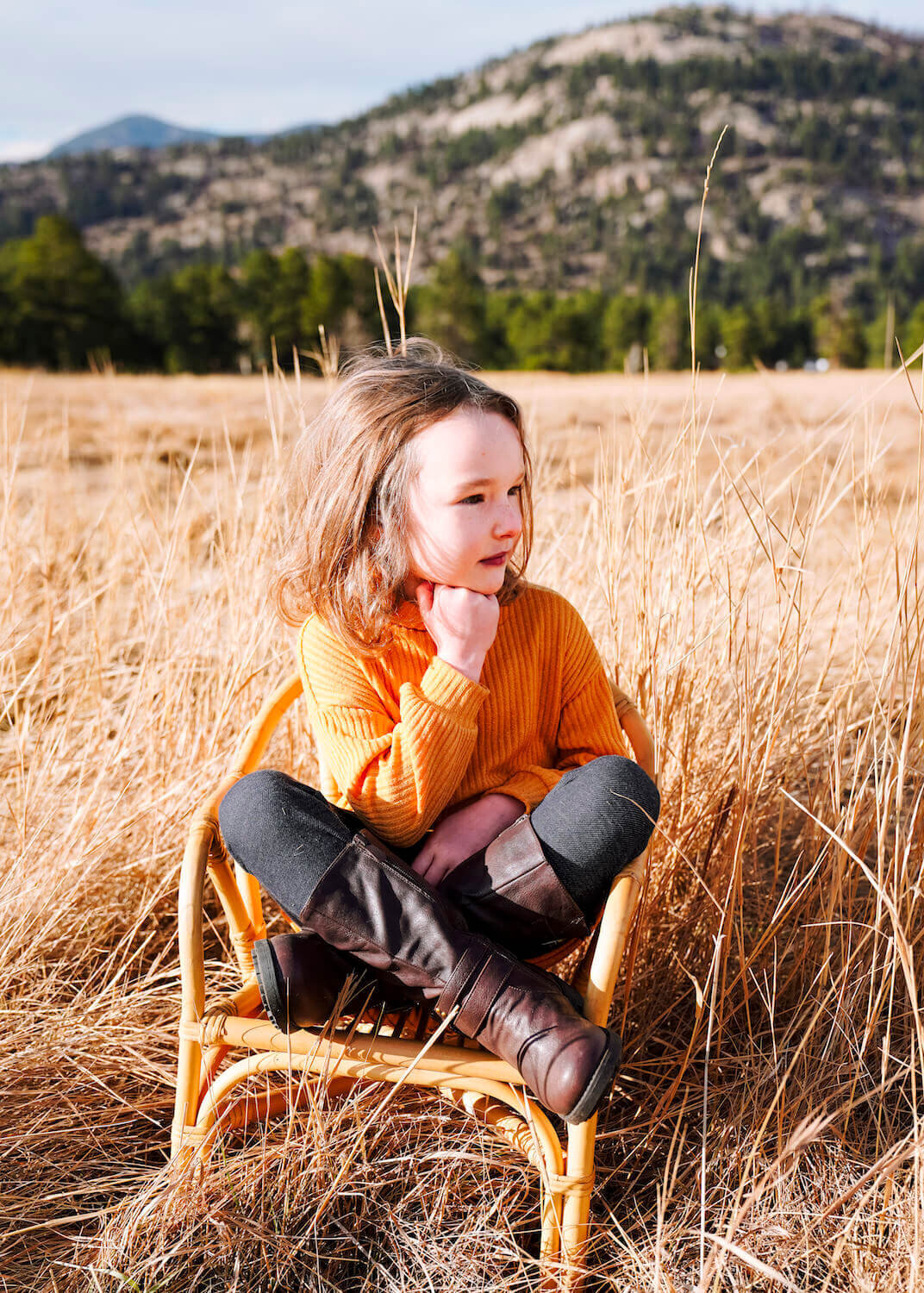 denver co family photographer - young girl in orange sweater sitting in field