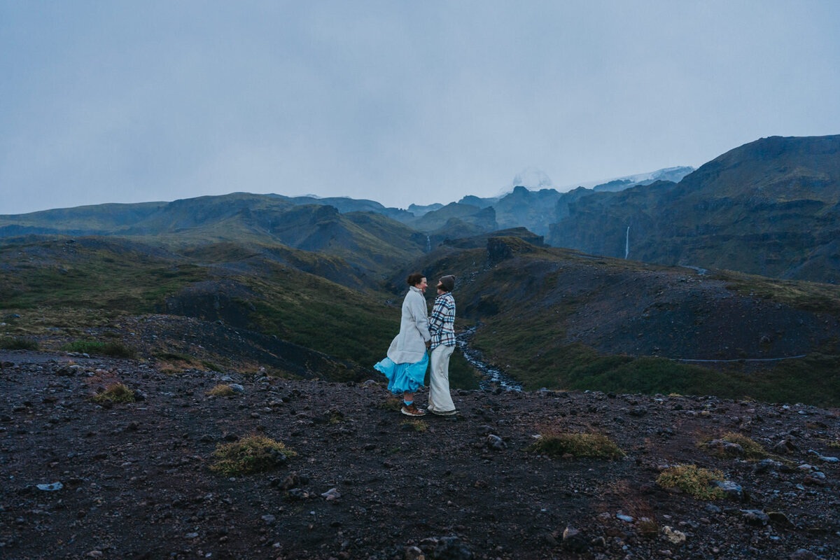 Women hold hands during their vow exchange on the black sand beaches of iceland 