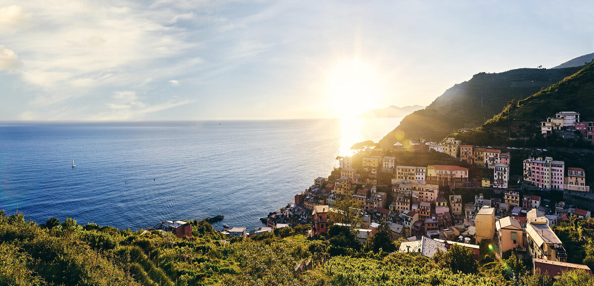 Blick auf die Küstenstadt Cinque Terre mit bunten Häusern im Licht der untergehenden Sonne – atmosphärische Landschaftsaufnahme mit mediterranem Flair