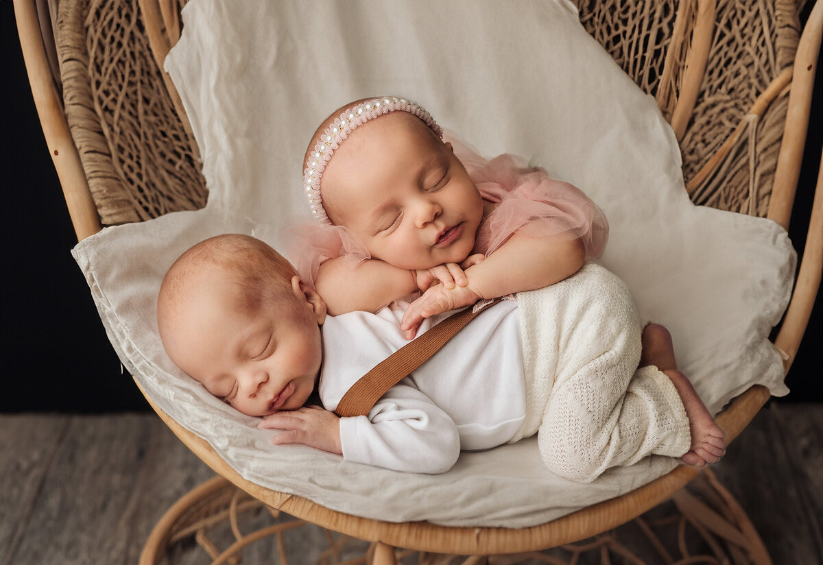 Newborn twins posed on top of eachother on boho chair and studio maternity session.