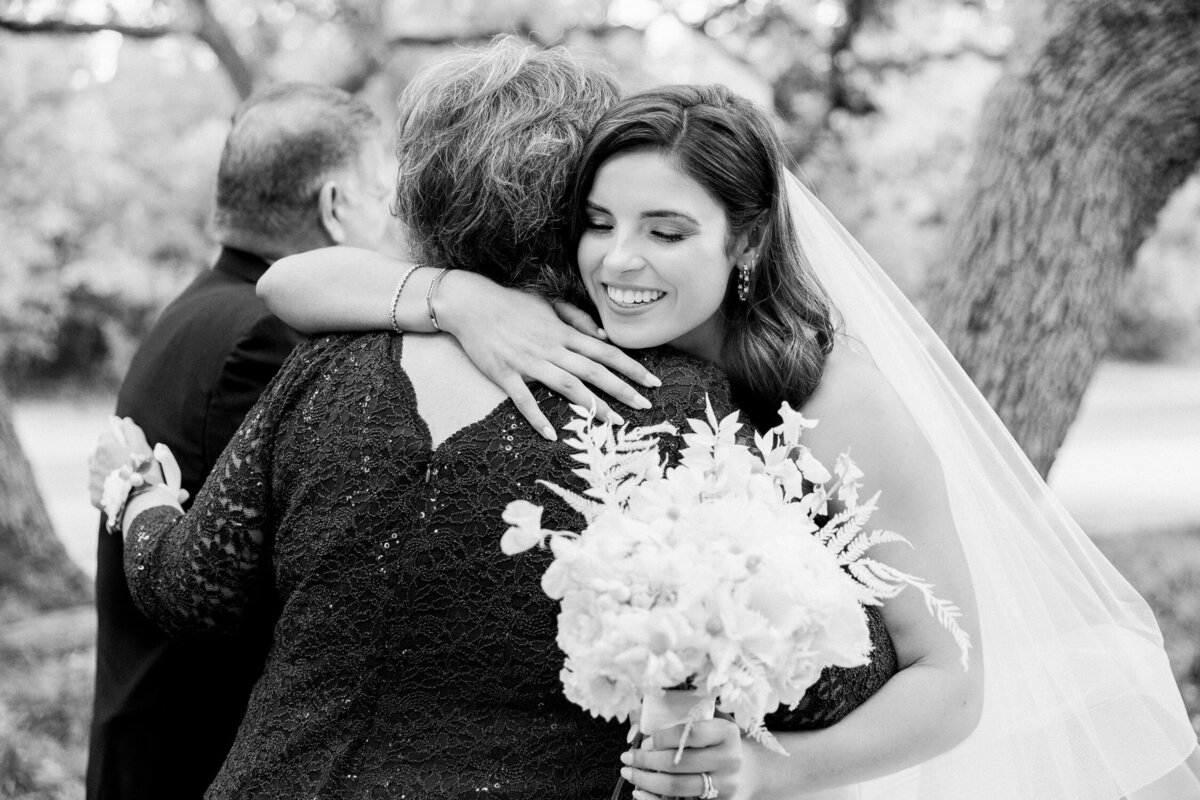 bride hugging mother and smiling on wedding day black and white