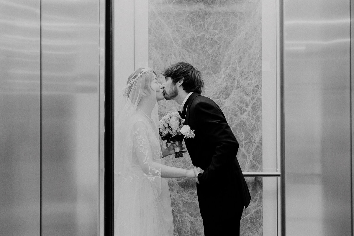 Black and white photo of a couple kissing inside the elevator at the Brisbane Registry Office after their ceremony.
