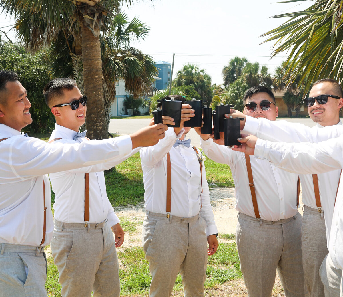groom and groomsmen cheering with black flasks in Panama City Beach by Florida wedding photographer Amanda Richardson Photography