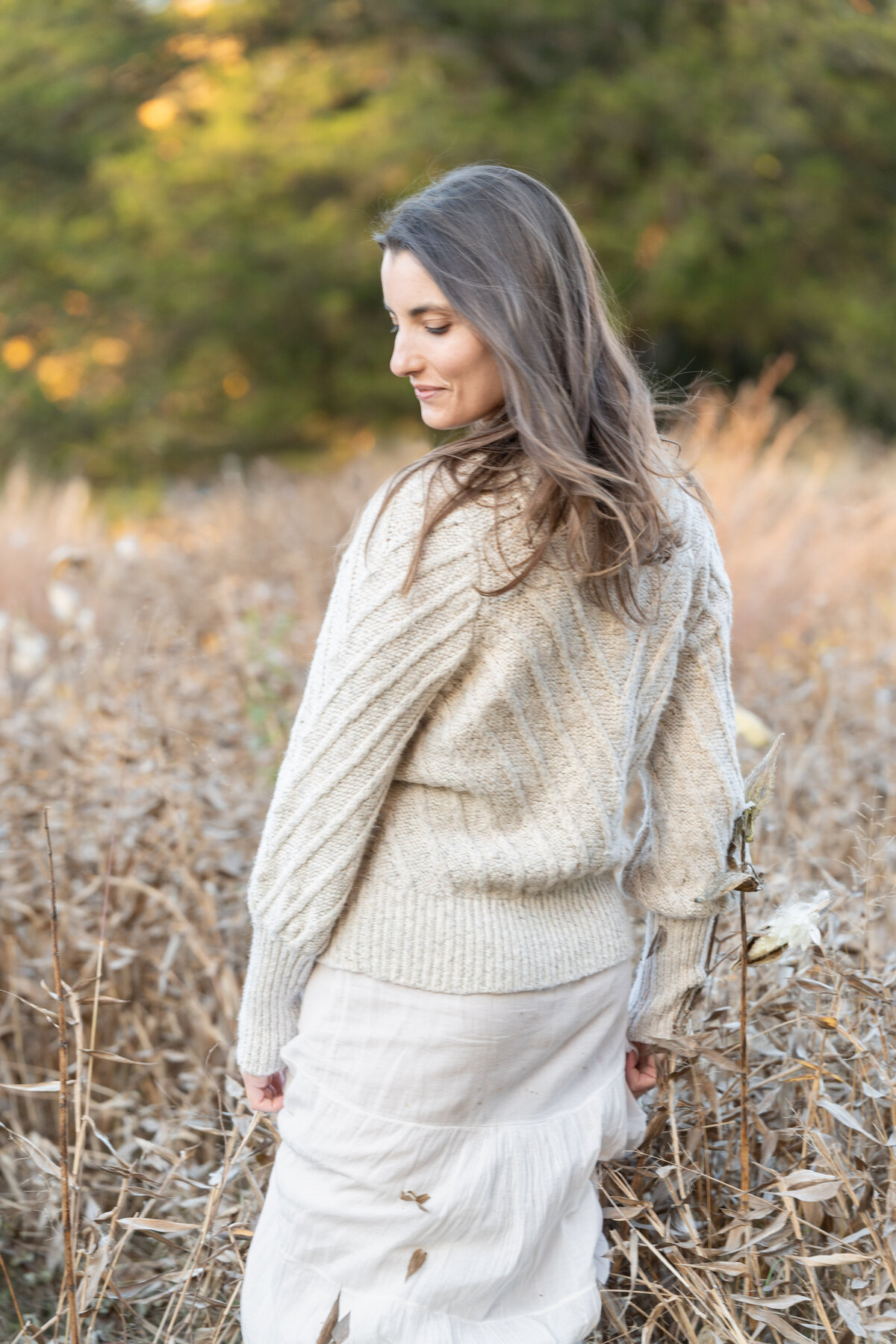 woman looking over shoulder in fall field of tall grasses