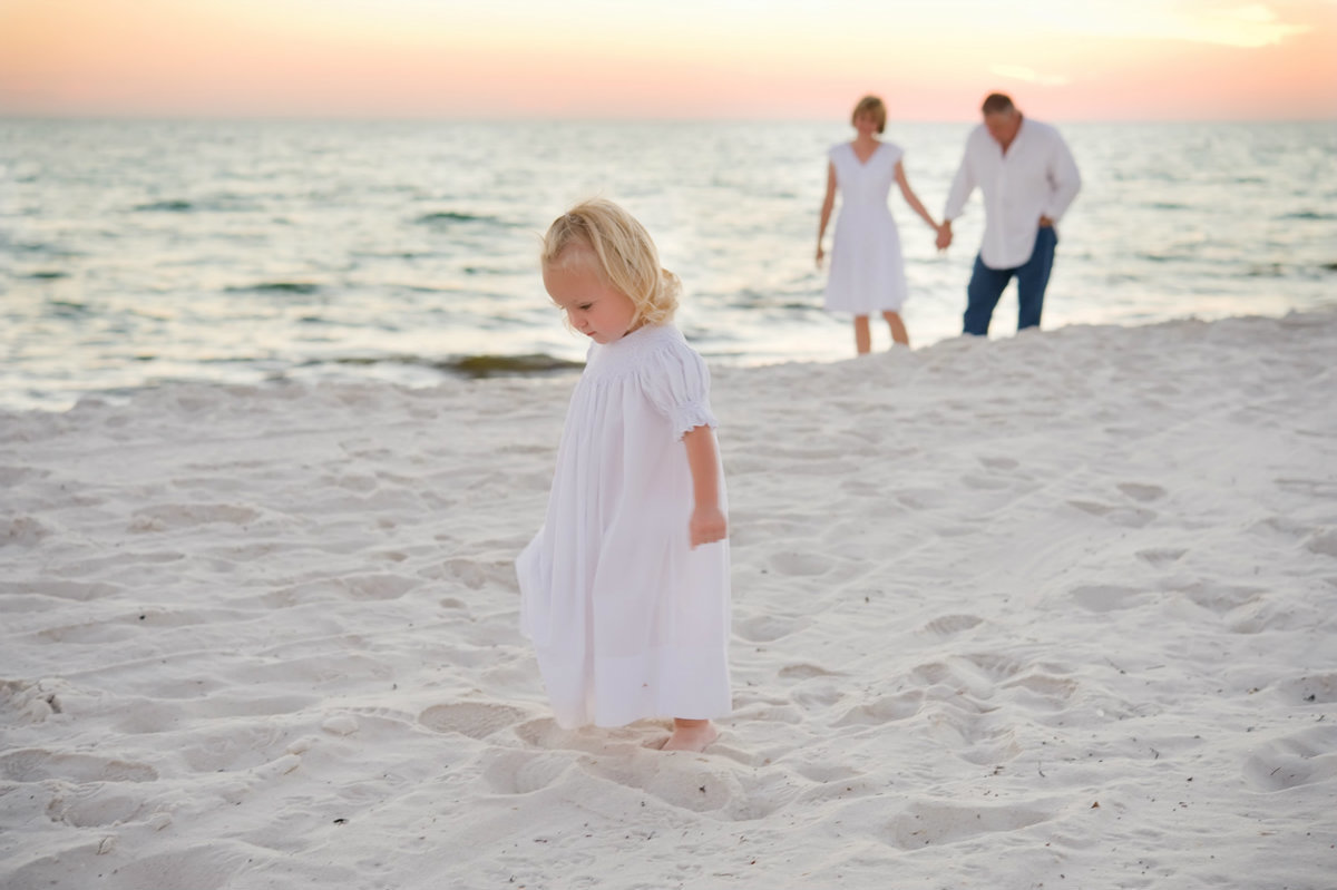Small child with parents walking on Orange Beach Alabama