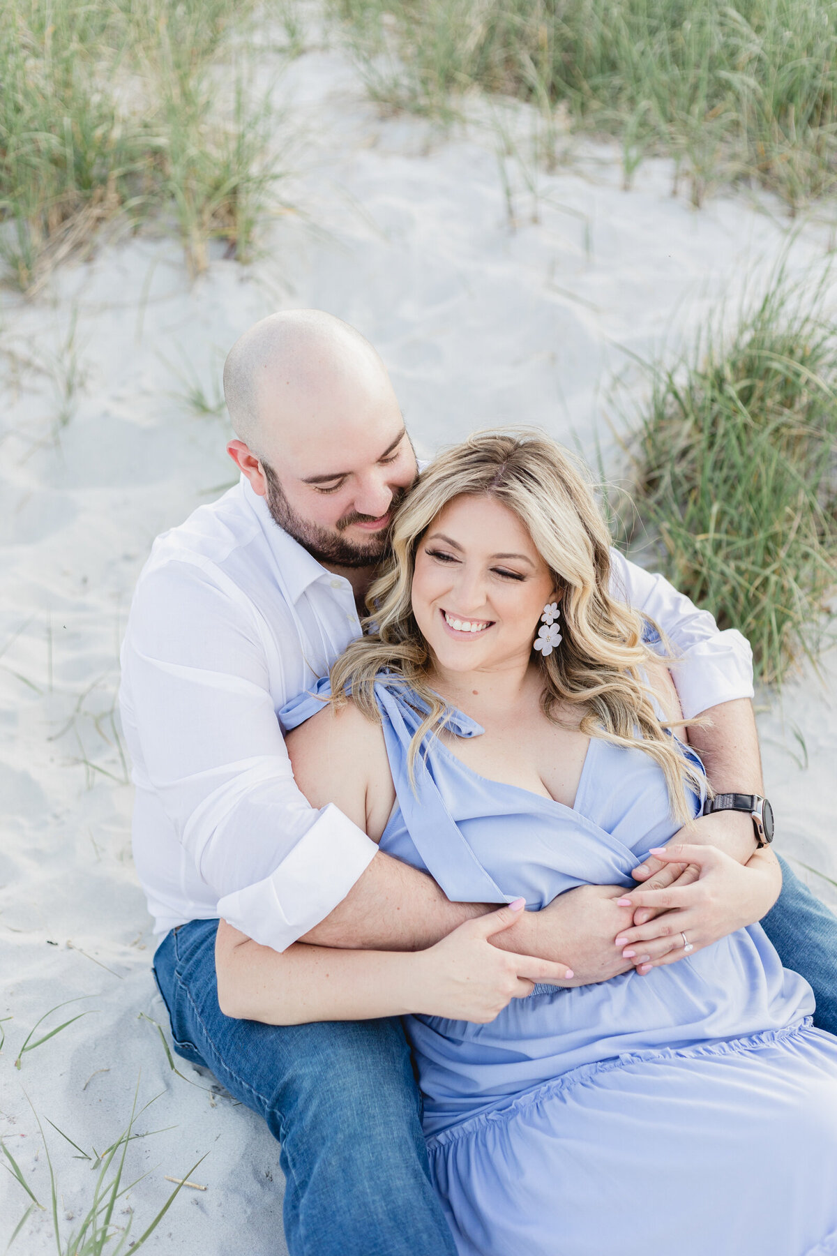 A couple cuddle on the dunes of a beach on the North Shore