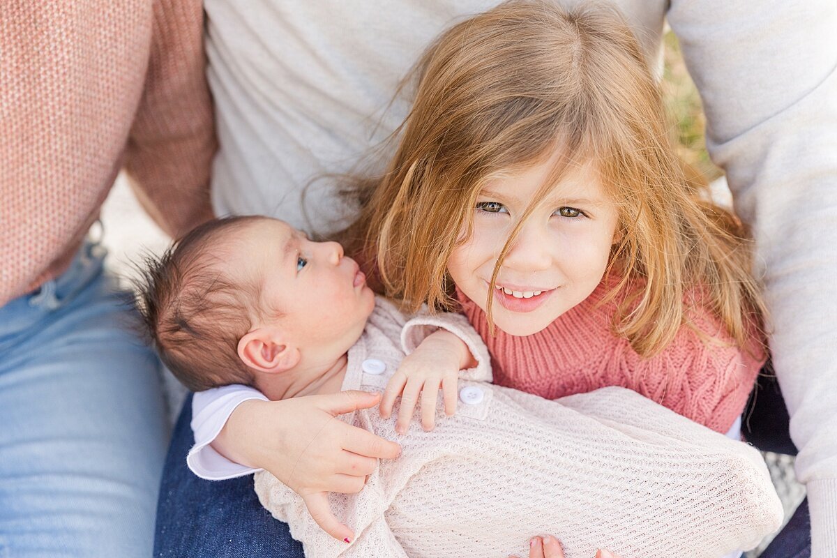 girl hold baby sister  during outdoor newborn photo session with Sara Sniderman Photography in Natick Massachusetts