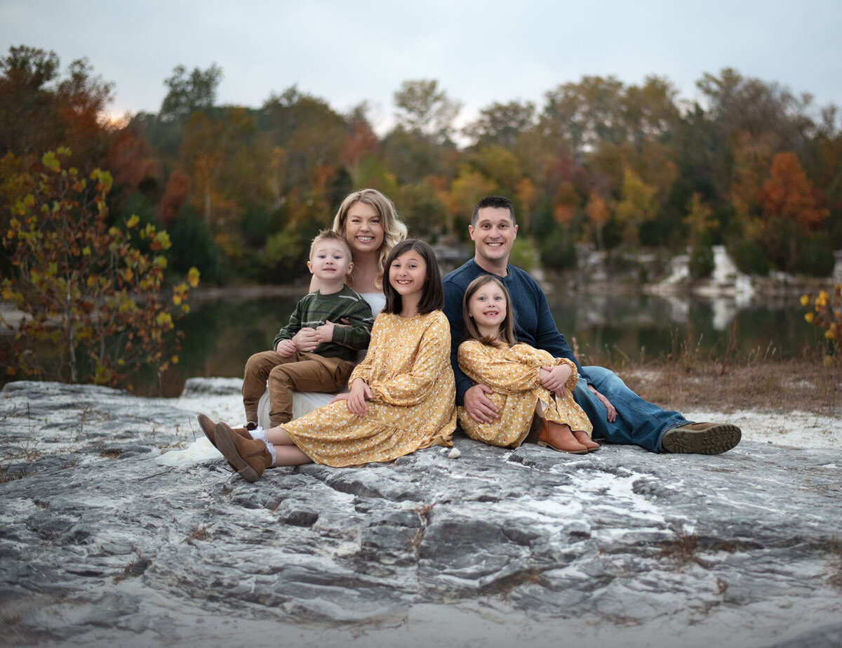 family sitting on a rock in fall by st. louis family photography