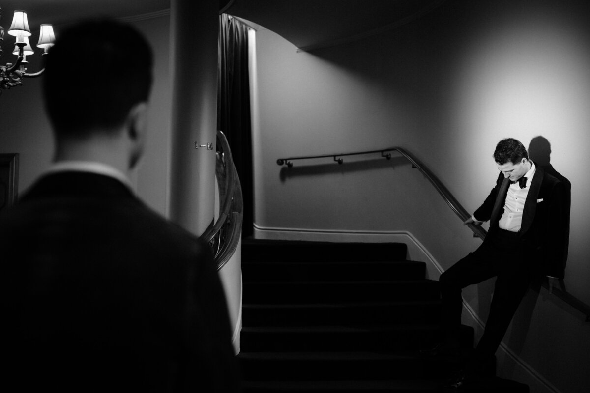 A groom looking at his groom on a spotlight at a staircase in Regal Cinema.