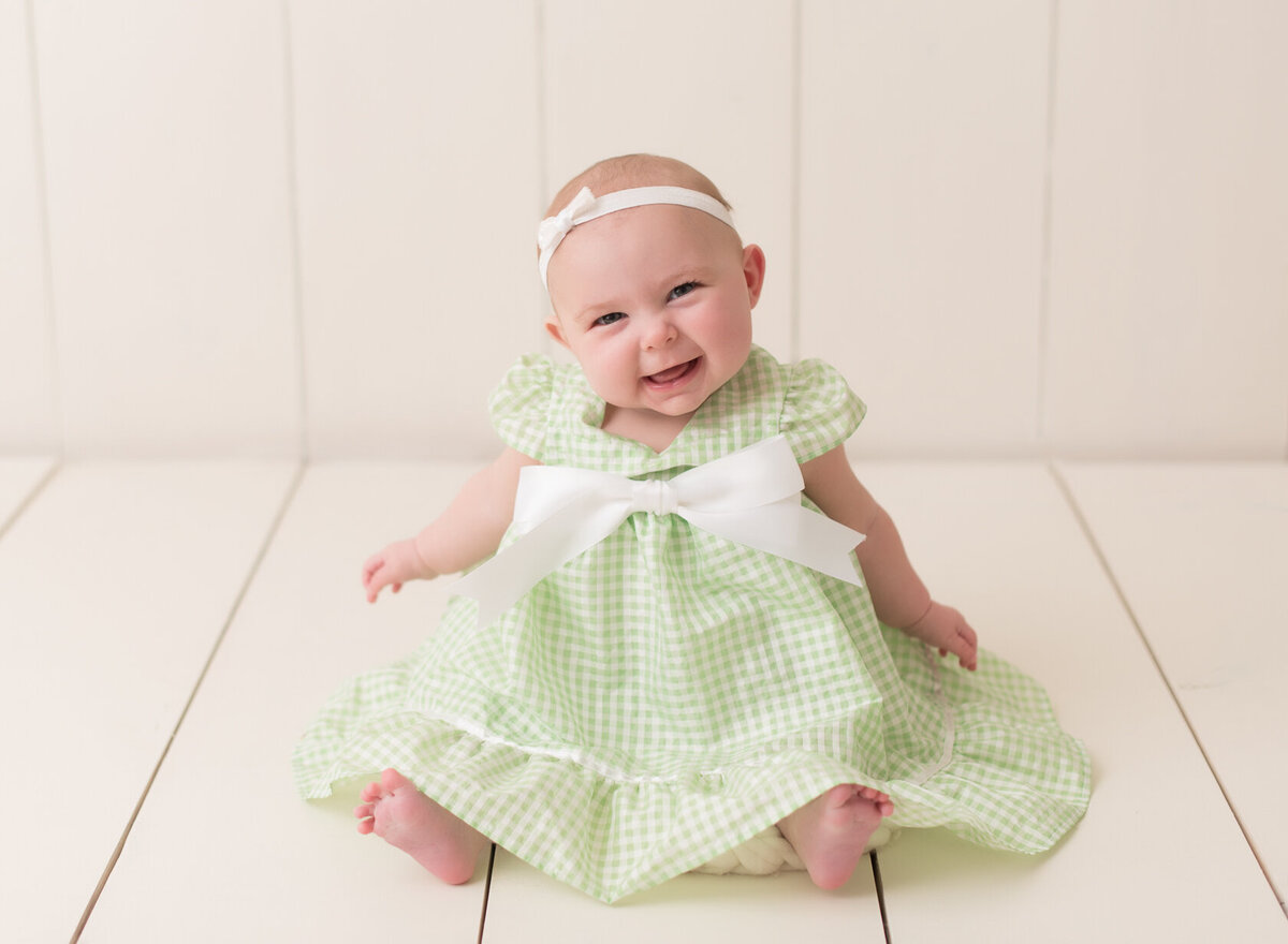 Smiling baby in green dress photo session in Houston