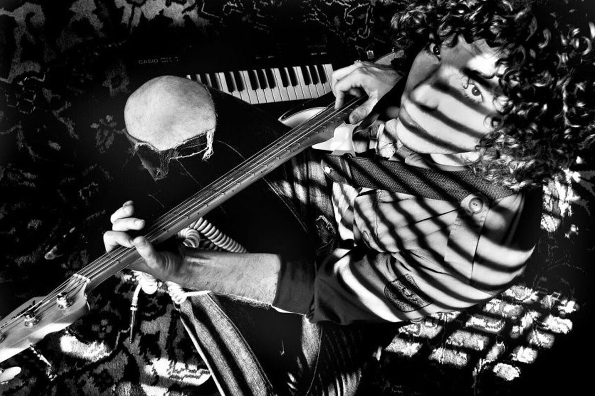 Musician Portrait Steve Bays black and white holding guitar keyboard beside him and shadows of venetian blinds running across his face and body high angle perspective Just Play Something Gallery