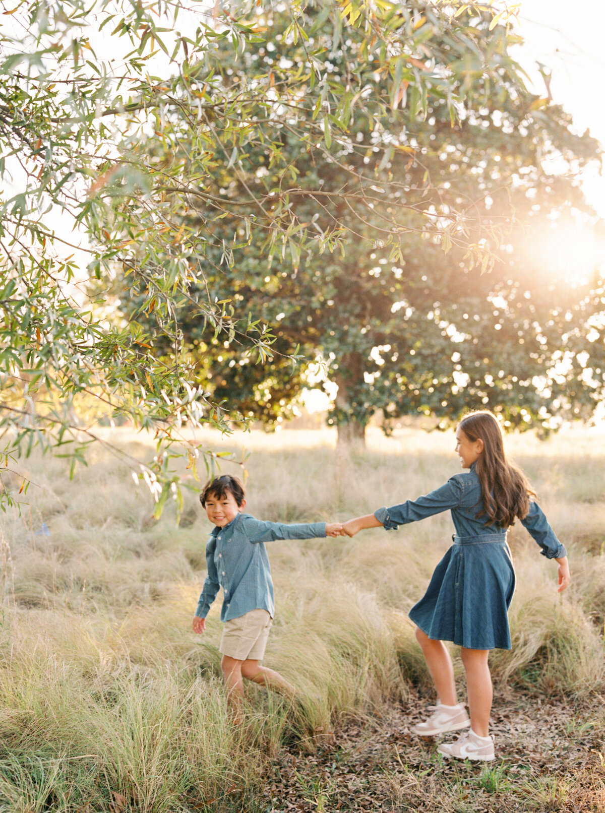 Siblings play in a field. Image by Raleigh maternity photographer A.J. Dunlap Photography.