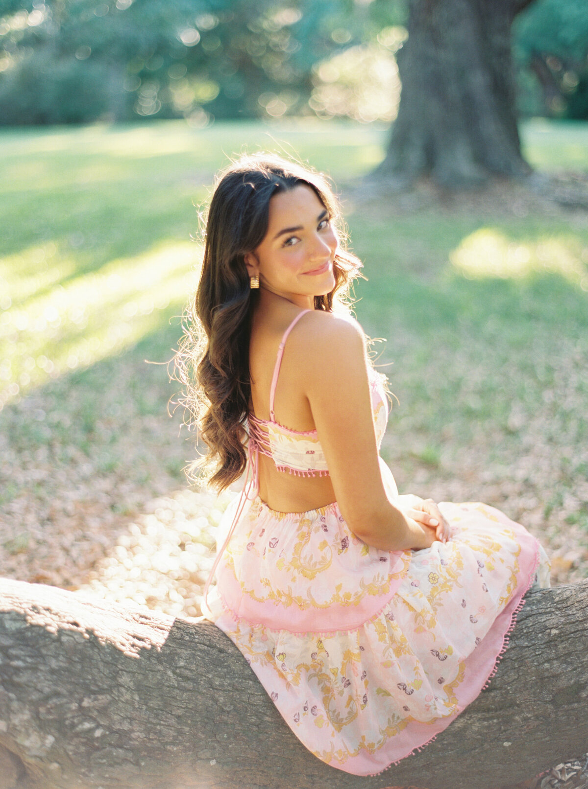A radiant senior portrait surrounded by blooming flowers at Jungle Gardens, capturing natural beauty and elegance on film by Morgan Alysse, Louisiana film photographer.