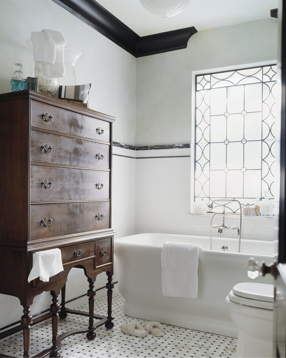 Panageries Residential Interior Design | Tudor Revival Estate Guest Bathroom with Stain Glass Window and Buffet for Towel Storage next to a big luxurious tub