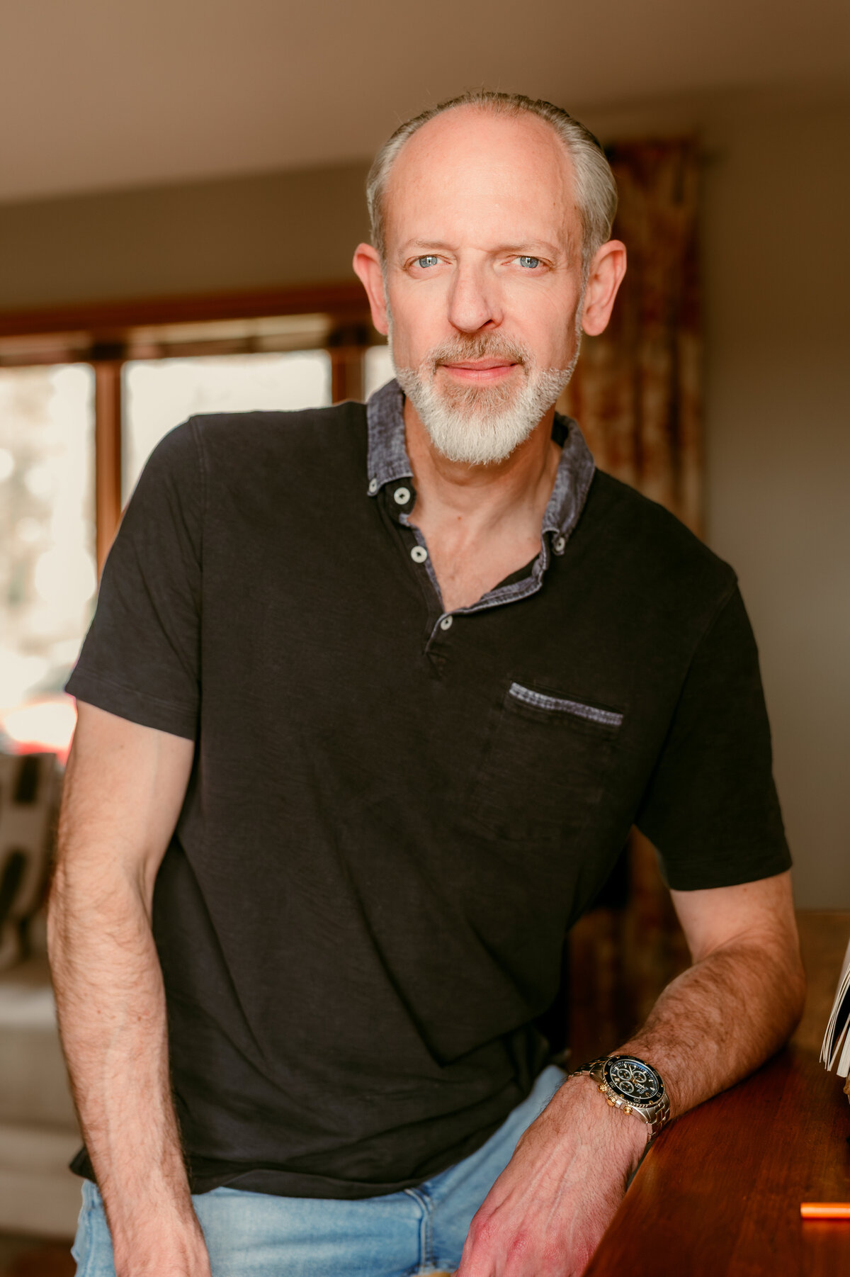 Thoughtful headshot of a man in his 50s at his sketching board, captured in natural light to reflect creativity and depth for dating profile