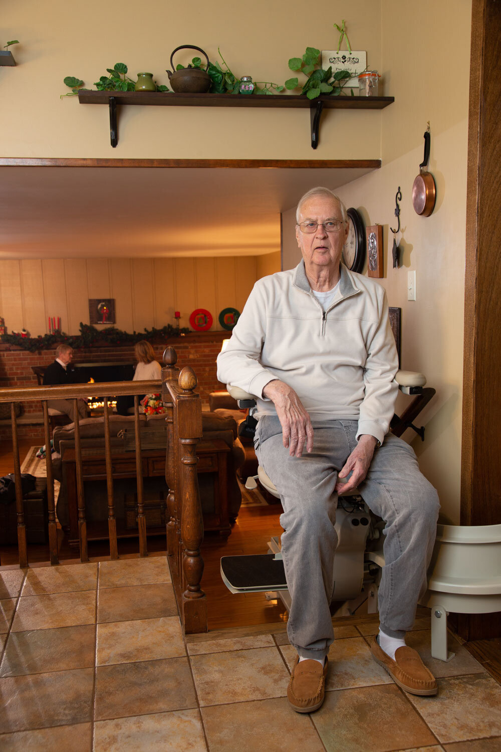 An elderly man sits in a chair in a living room