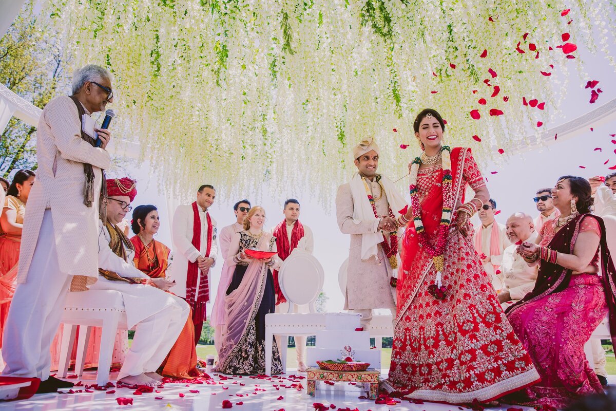Roses being thrown over the indian bride and groom during the hindu ceremony as they walk around the fire on their wedding day at edgewood country club nj