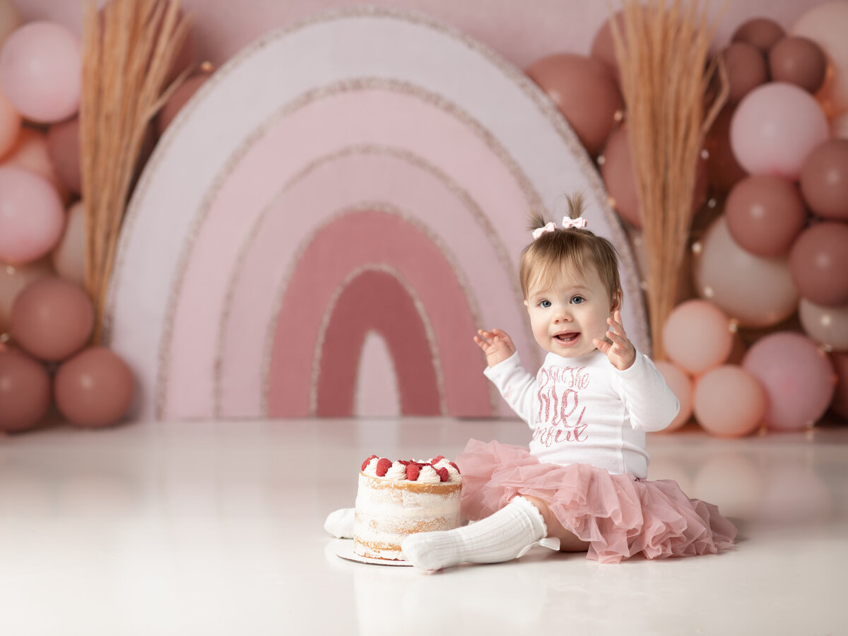 one year old girl in pink and white tutu for cake smash photography