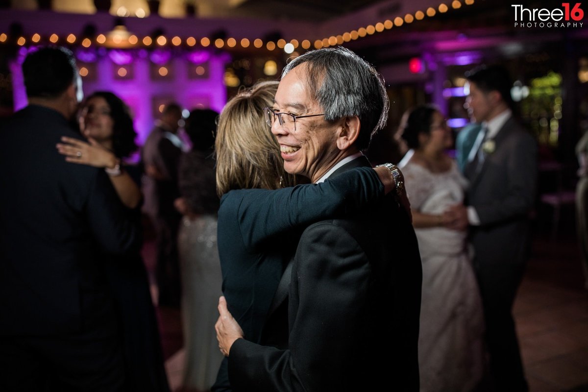 Guests smile and dance at wedding reception