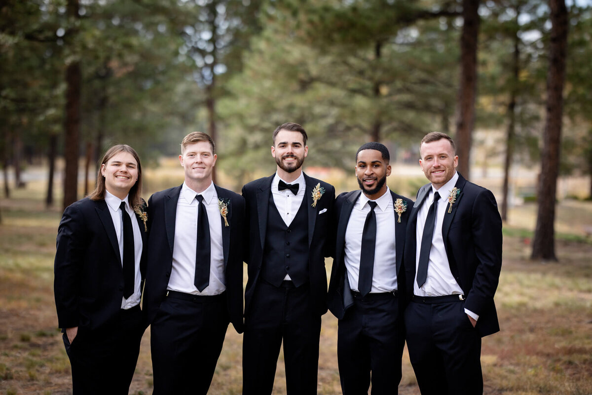 A groom stands with arms around his groomsmen