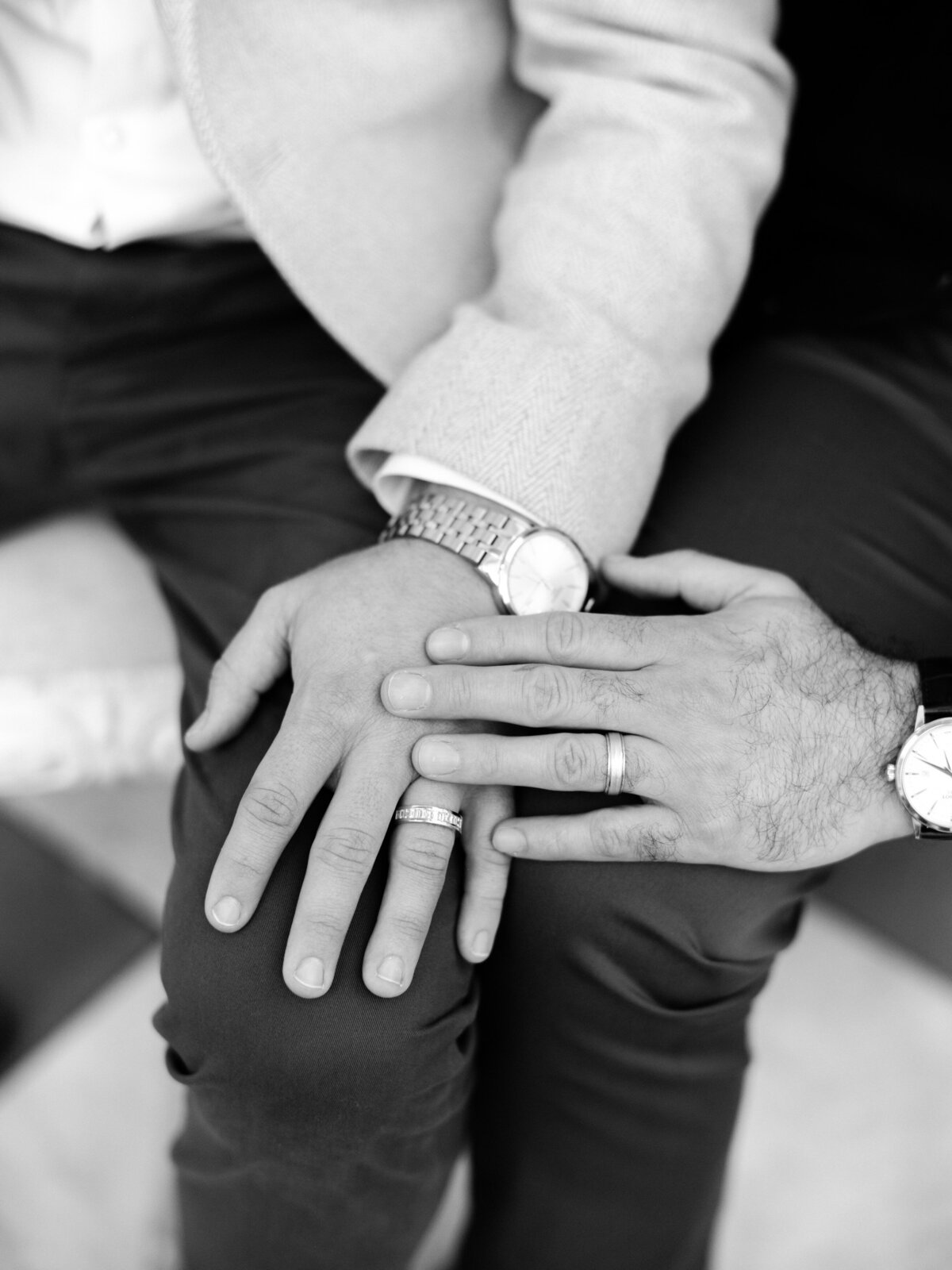 A heartfelt close-up captures the intertwined hands of a same-sex couple showcasing their wedding rings, symbolizing their commitment and deep bond in a soft, intimate composition.