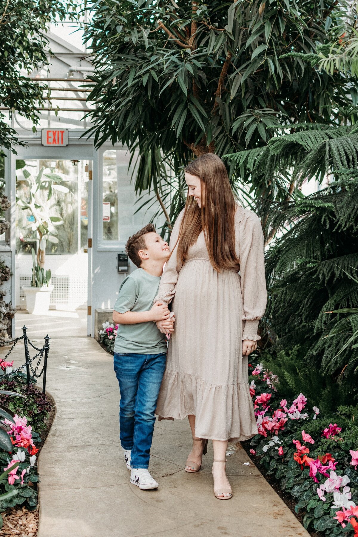 mom and son walking through the Wilder Park COnservatory, elmhurst il, smiling at each other surrounded by greenery