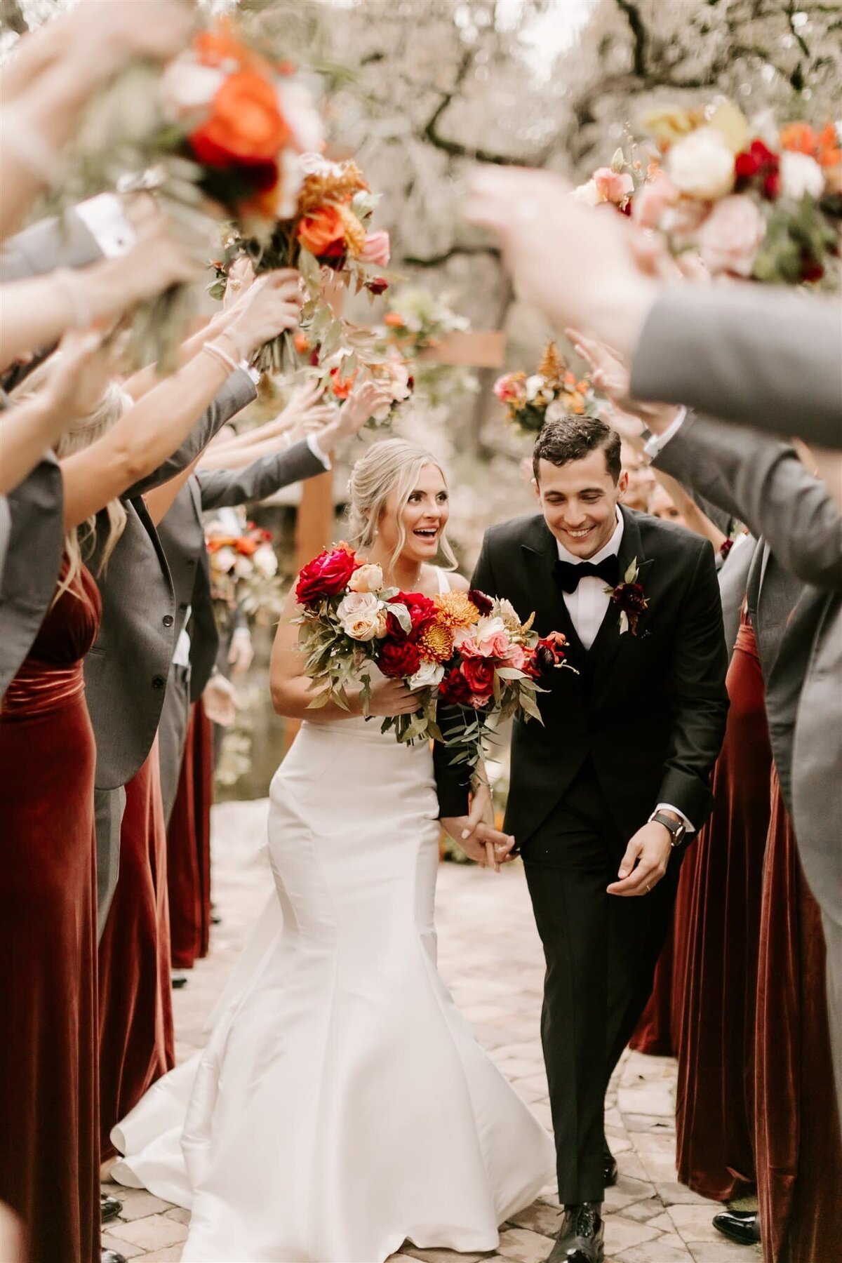 bride and groom laugh as they walk through a tunnel of their wedding party