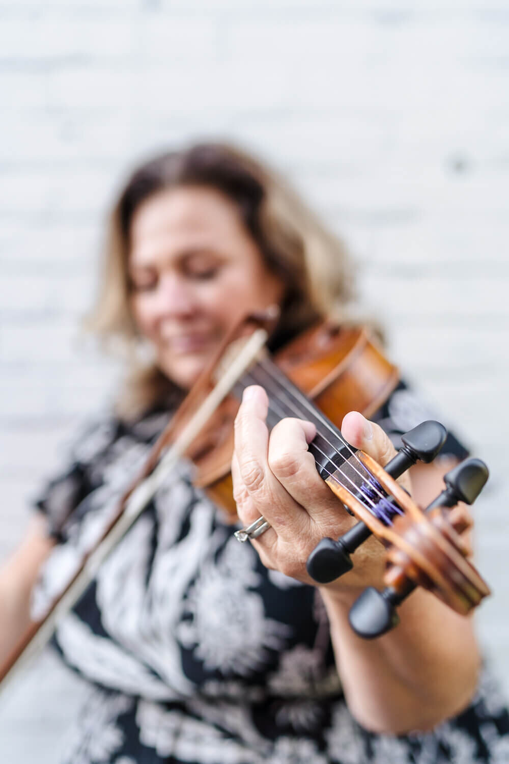 out of focus woman playing violin with hand in focus for social media content