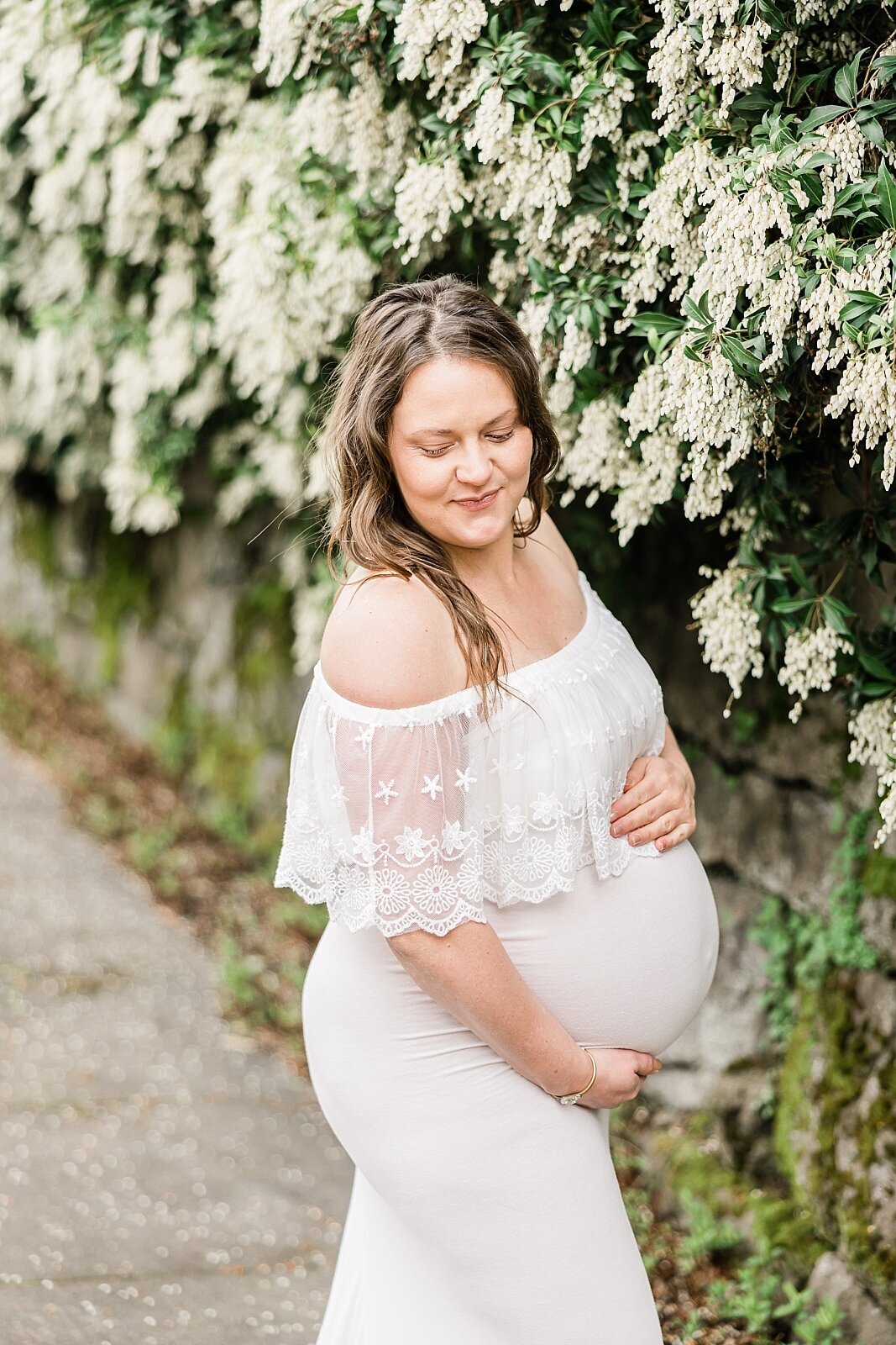 pregnant mom in white dress for maternity pictures with white flowers