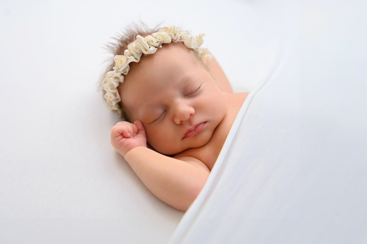 newborn girl side view of her laying on a white background for her newborn photos