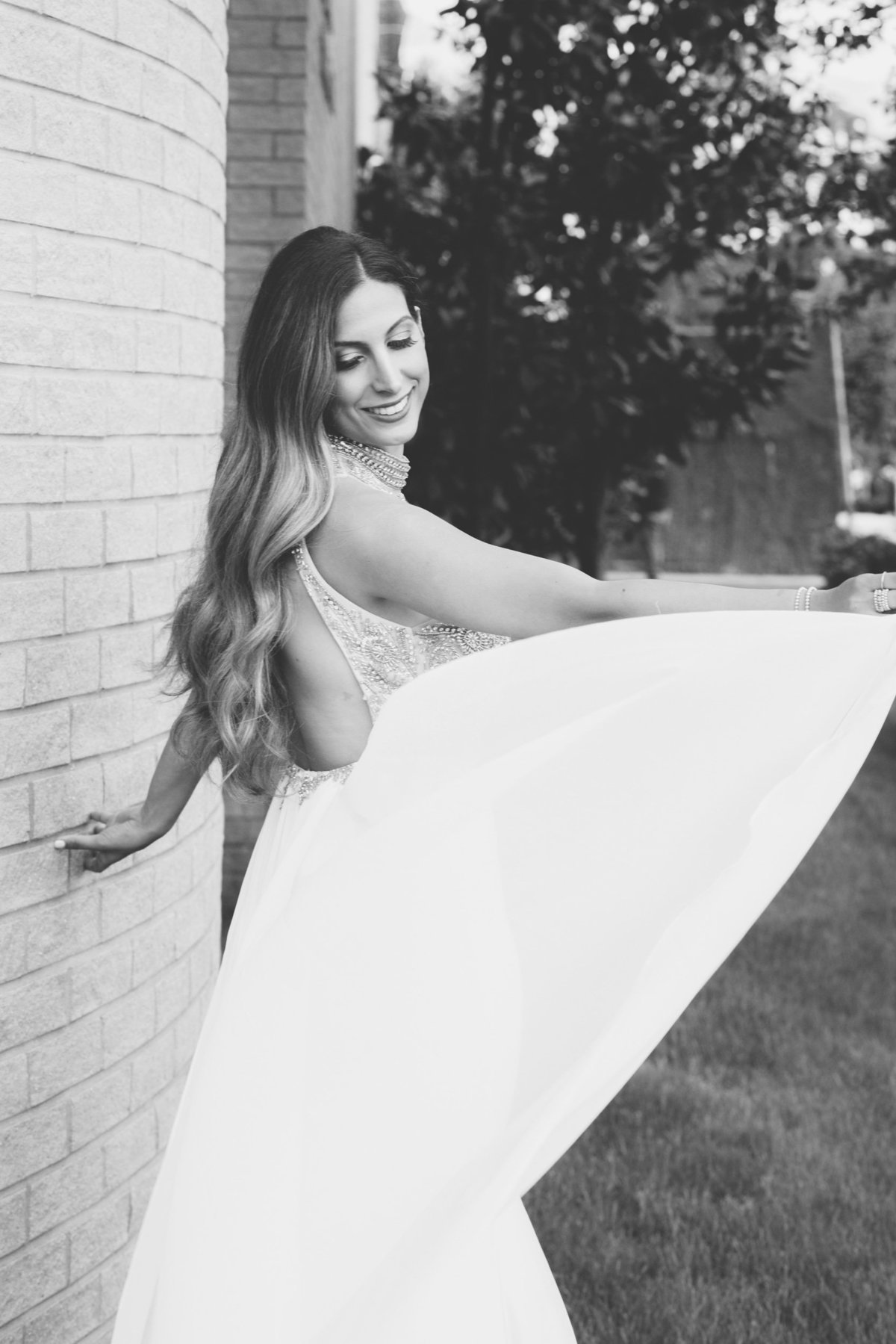 black and white photo of bride flowing her dress outside wedding reception at Sephardic Temple