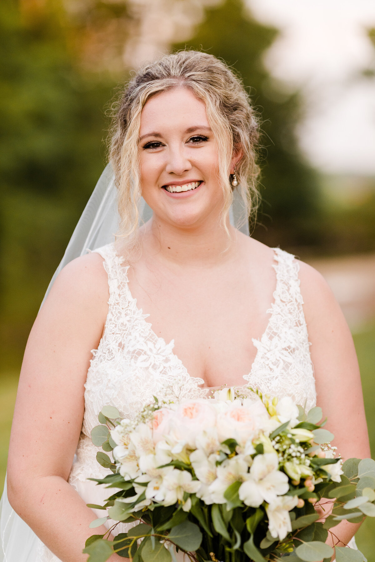 Bride smiling at camera holding light pink flowers
