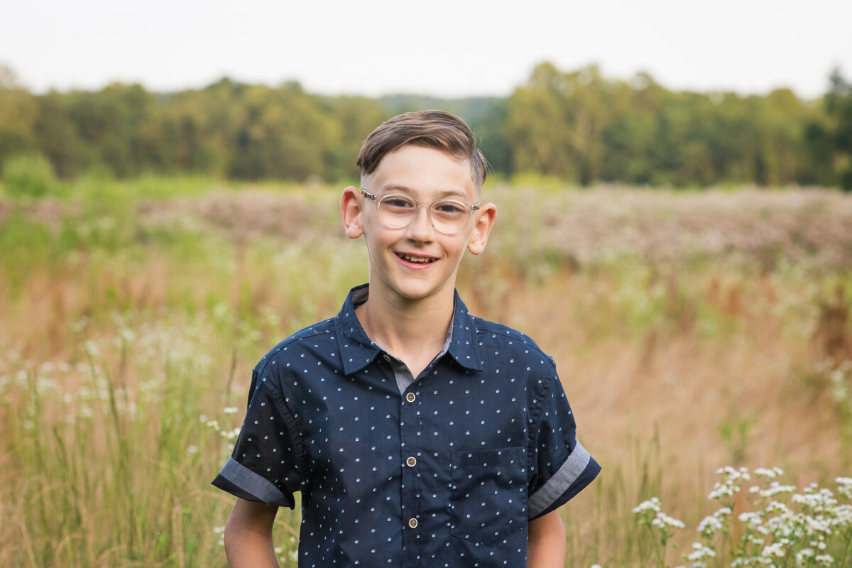 preteen boy smiles in field of tall grass at Everett Covered Bridge