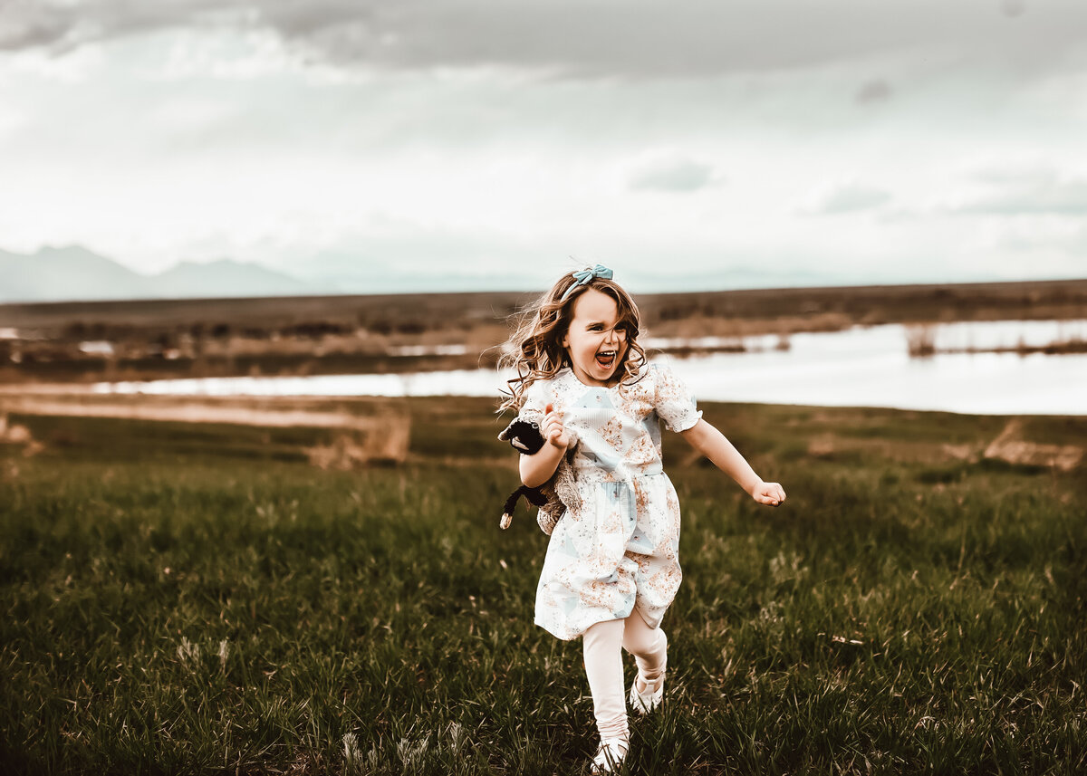 Fun family photoshoot in Westminster Colorado girl runs though field with her lovey