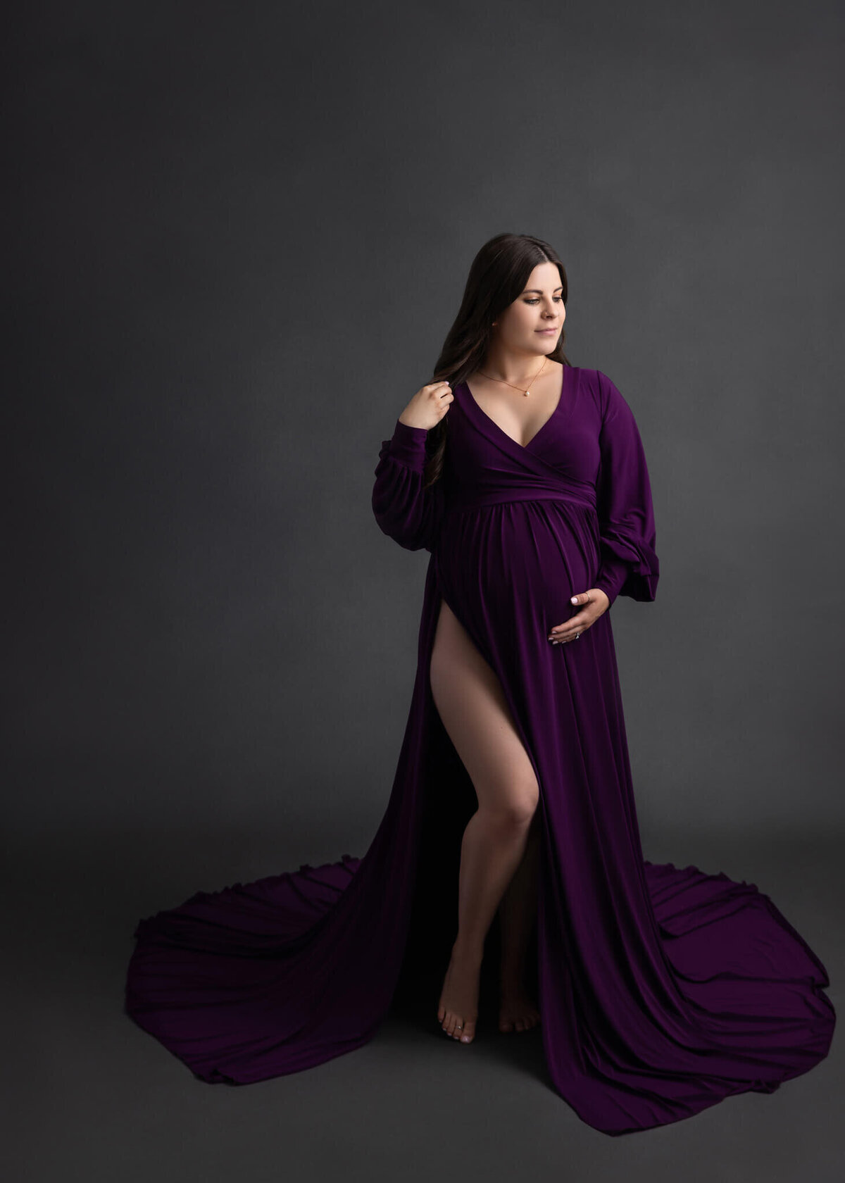 pregnant mom cradling her belly wearing a purple dress