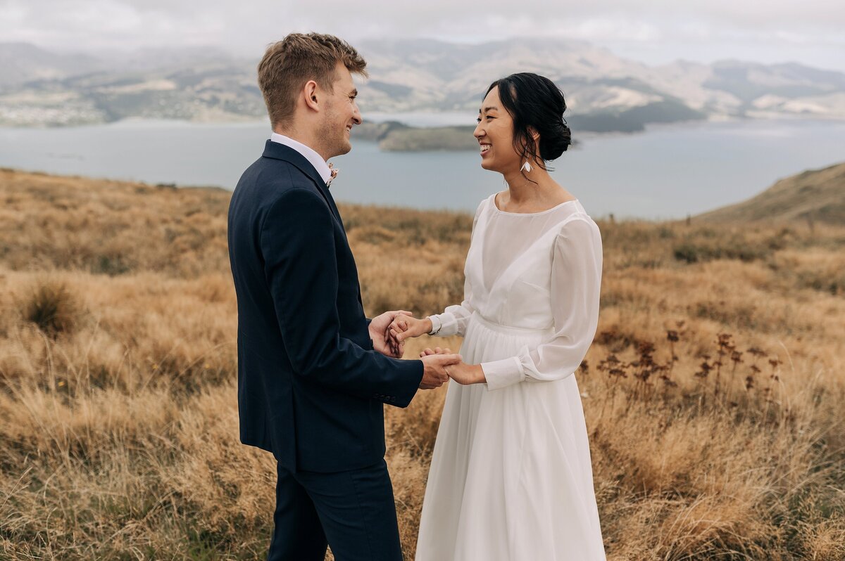 bride holding groom hands dry grass port hills christchurch candid moment documentary style