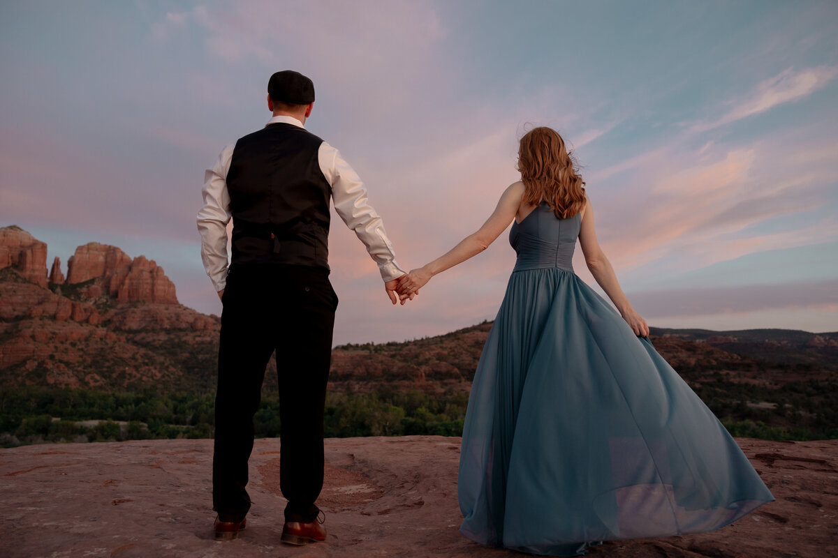 Couple standing against red rock backdrop during Sedona engagement session