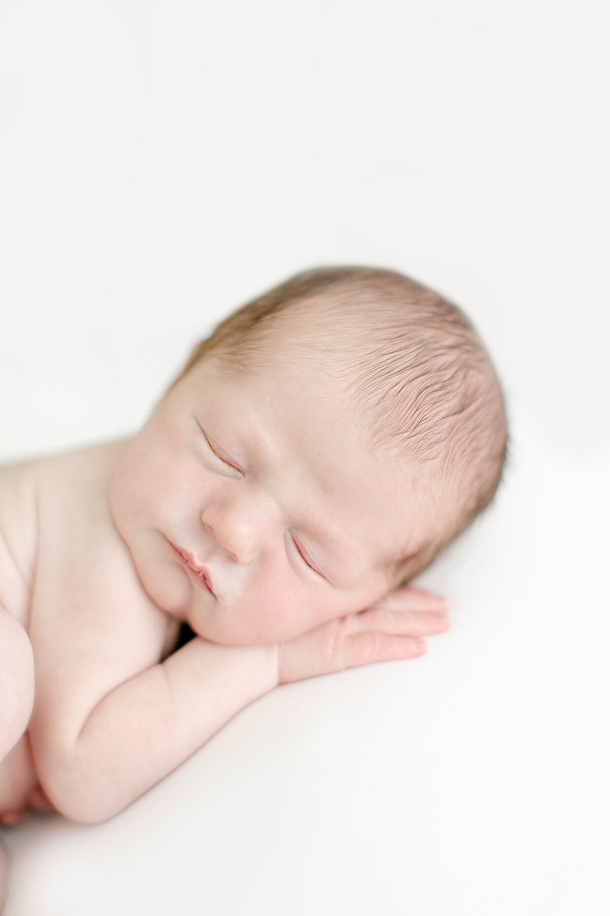 close up of newborn laying on his belly with head on hand