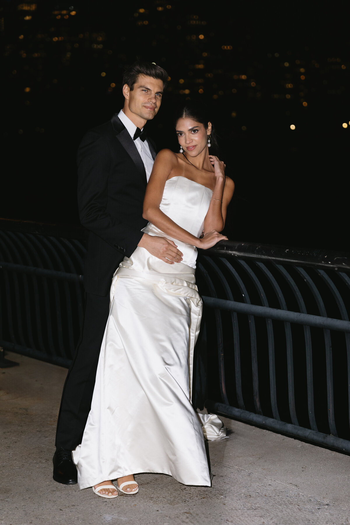 Romantic wedding portrait taken at night with city lights in the background.