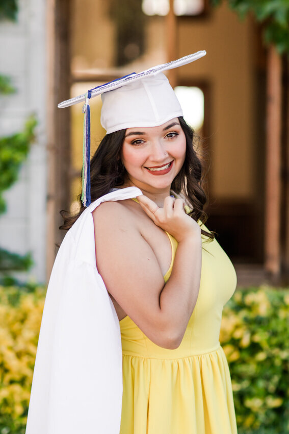 senior girl in cap with gown over shoulder