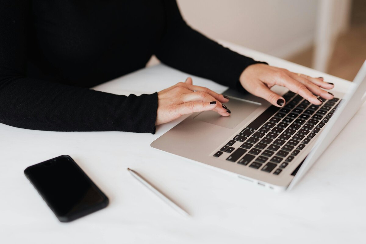 Contact page image woman in black sweater typing on laptop