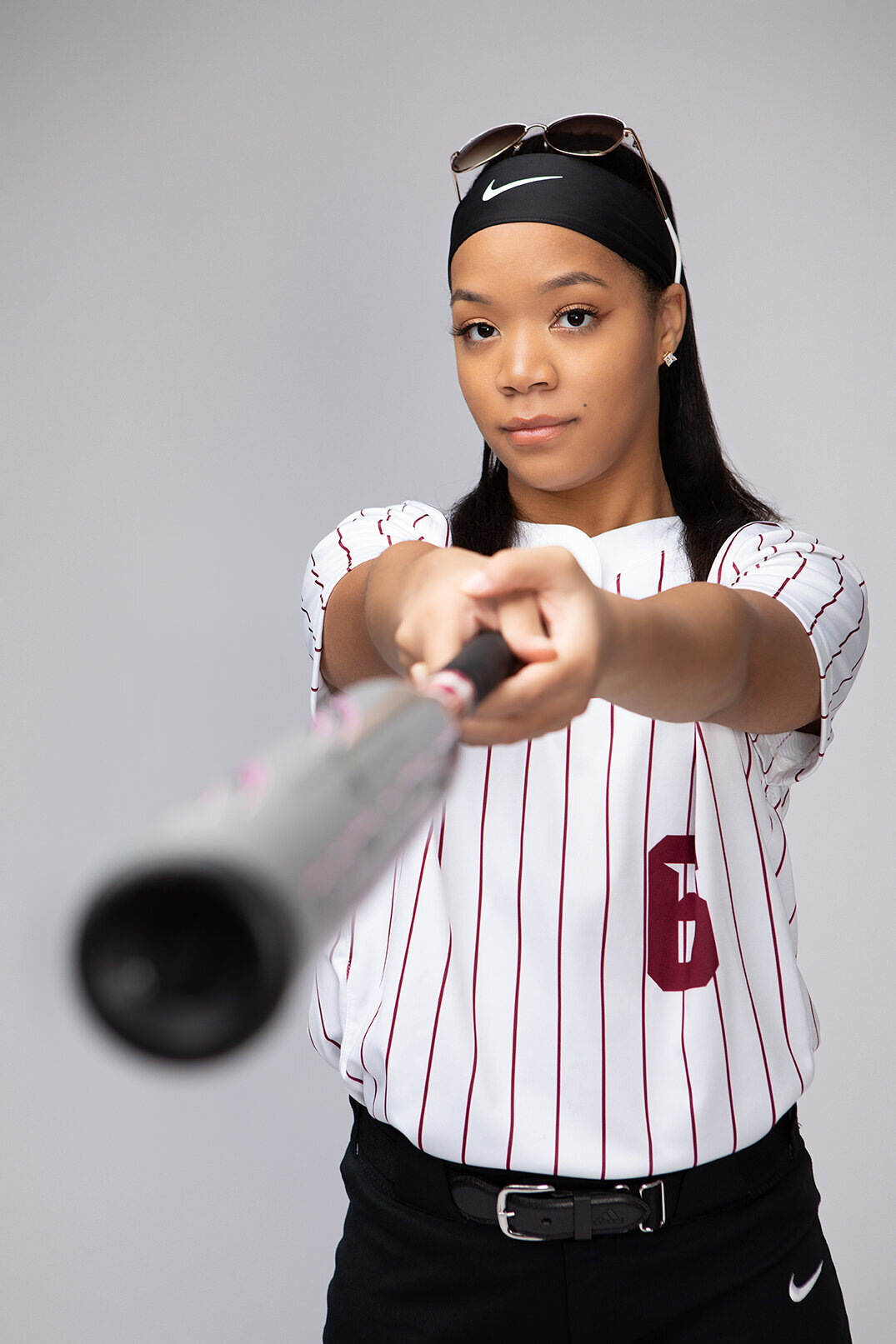 senior in softball uniform holding bat