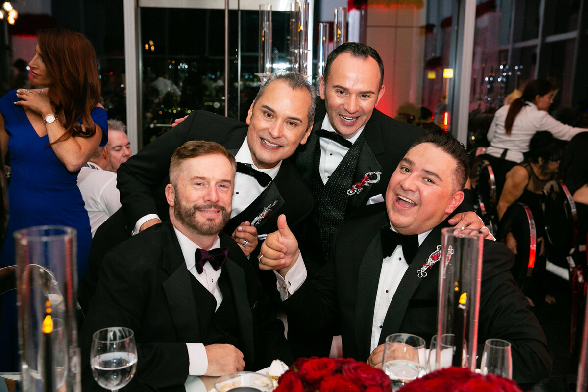 Four men laughing and smiling in tuxes